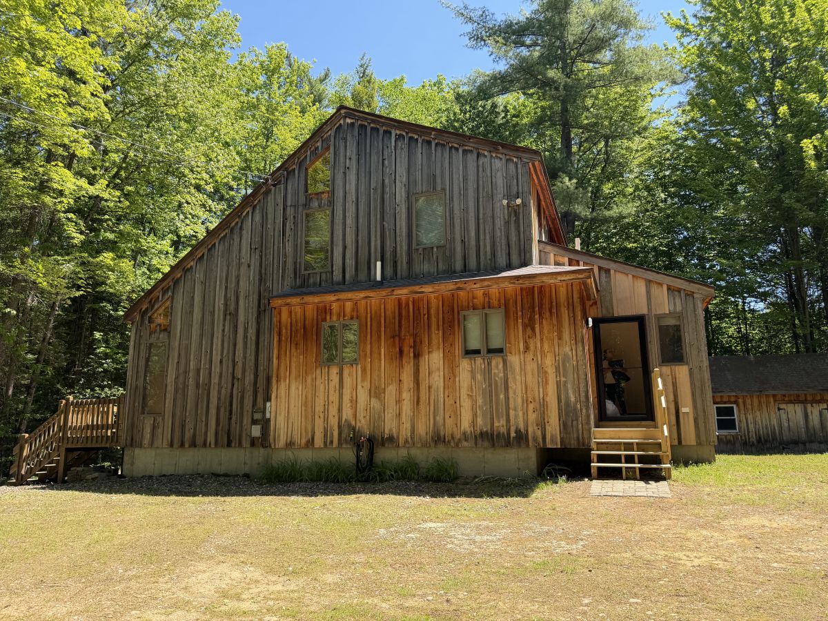 A rustic two-story cabin nestled in a forested area in Sanbornton, NH.