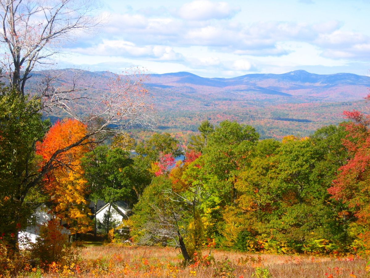 The property sits nestled among vibrant autumn foliage with sweeping mountain vistas stretching across the horizon, offering a peaceful retreat in nature's seasonal splendor.