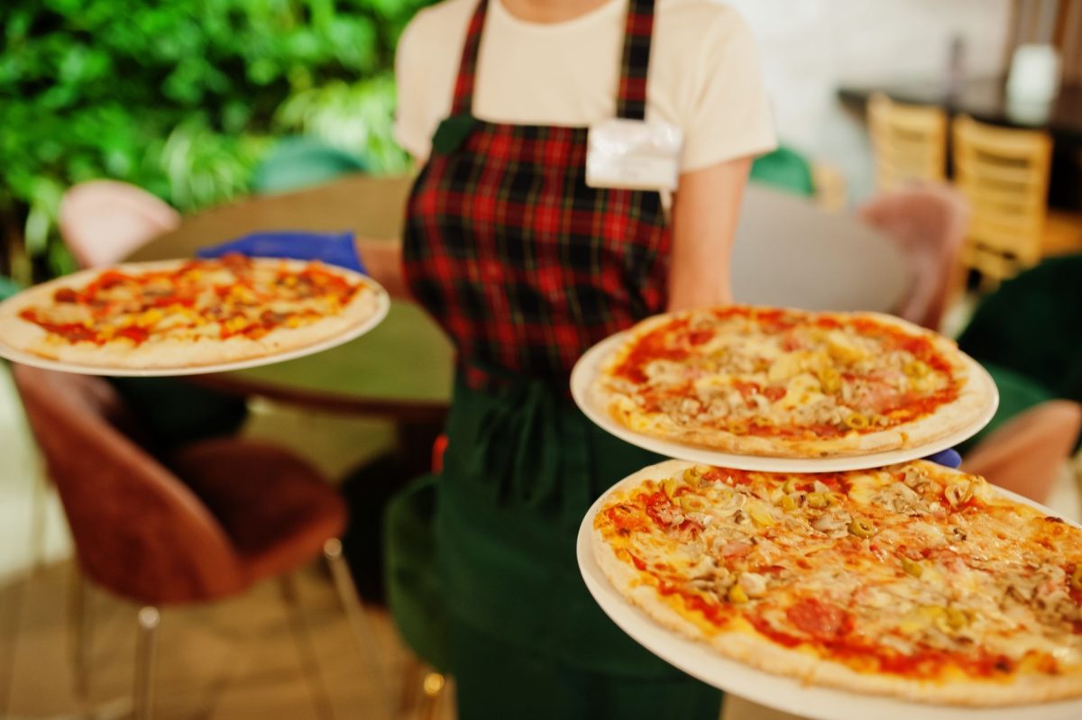 waiter carrying three pizzas